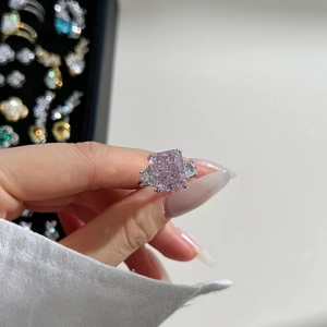 Macro shot of a pink square gemstone ring with side stones in silver claw setting