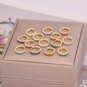 Macro shot of 18K gold earrings with colorful zircon stones in a jewelry box