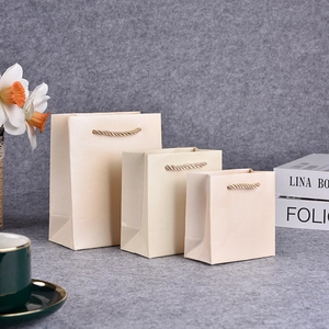Mini beige jewelry paper gift bags with woven rope handles in three sizes on felt background