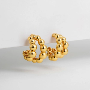 Detailed view of two-tone golden C-shaped bubble hoop earrings with polished bead texture