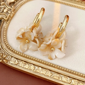 Macro view of C-shaped flower petal earrings on a vintage gold relief tray