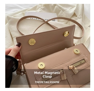 Détail des doubles boucles magnétiques dorées et texture cuir kaki du petit sac carré