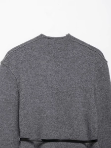 Close-up of a dark grey wool coat featuring a slim black belt with fine knit texture
