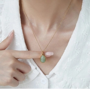 Detailed close-up of a drop-shaped green stone pendant on a gold 18K plated chain