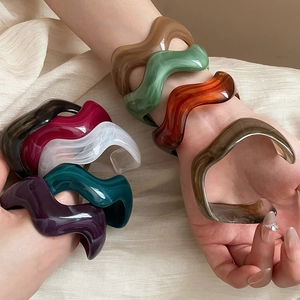 Close-up of wavy acrylic bangles in assorted colors with a polished resin texture