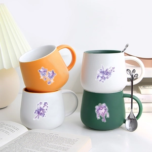 Stack of ceramic mugs with purple floral magic motifs and leaf-shaped stainless steel spoons