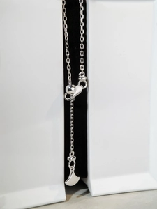 Macro detail of S925 sterling silver chain with adjustable slide bead and fan-shaped charm