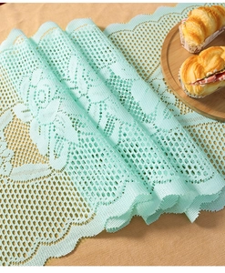 Close-up of mint green lace table runner with rose embroidery and scalloped edges