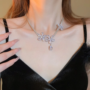 Close-up of a silver flower necklace with zircon pendants on a model's neck