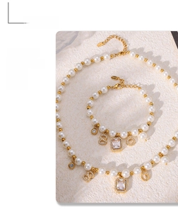 Detail view of pearl jewelry set with golden beads, zircon pendant and diamond letter charms