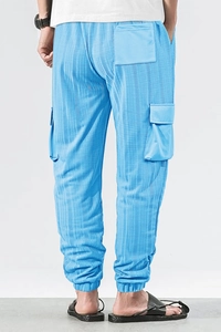Detail of blue cargo pants with waffle texture and large side pockets in back view