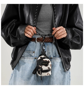 Detail of mini cow print crossbody bag with fashion label and braided lanyard strap