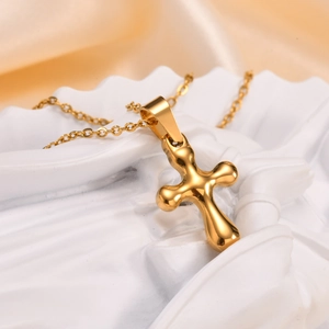 Detailed view of a puffy gold cross pendant on a fine O-link chain over white relief
