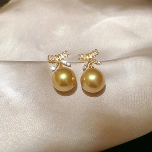 Detail of elegant bow earrings with sparkling cubic zirconia and champagne pearls