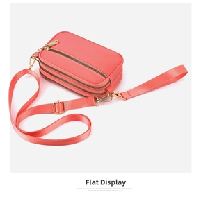 Detail of coral pink crossbody bag featuring three zippered pockets and golden hardware