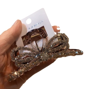 Golden bow hair claw clip with sparkling rhinestones shown from a front angle view