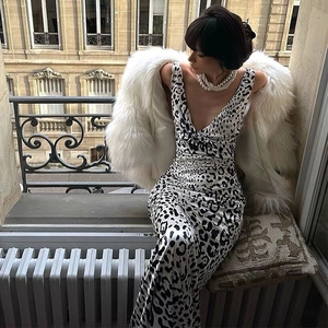 Détail de robe longue satinée léopard col V portée avec collier de perles et veste en fourrure