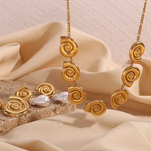 Detail of 18K gold plated shell necklace with white pearls on a natural stone background