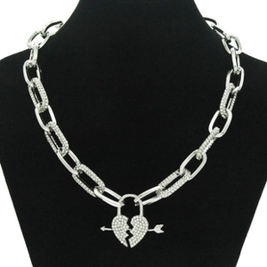 Macro detail of silver iced-out broken heart lock and arrow pendant on a heavy chain
