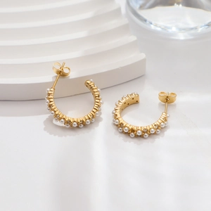 Detailed view of 18k gold C-shape earrings with inlaid pearls and sparkling crystals