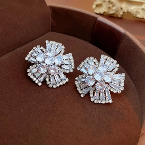 Macro detail of silver flower stud earrings with sparkling cubic zirconia on brown velvet
