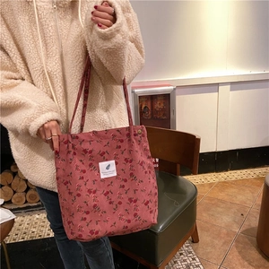 Close-up of pink corduroy tote bag with rose floral print and white woven label