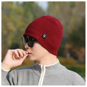 Close-up of wine red knit beanie with brand label and thick warm texture for winter
