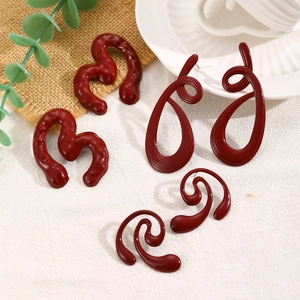 Three pairs of deep red geometric earrings with textured heart and spiral drop designs