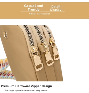Close-up of golden metal zippers and colorful woven strap on a beige nylon shoulder bag