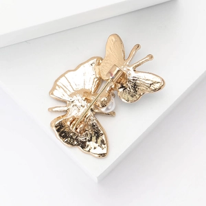 Macro shot of gold butterfly brooch back featuring safety pin clasp and pearl detail