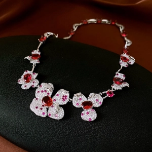 Detail of flower-shaped earrings with red oval stones and crystals on a black stand