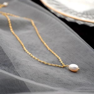 Elegant gold chain necklace with white teardrop freshwater pearl pendant on grey mesh