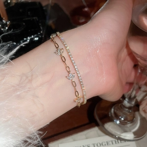 Detailed view of dual-layer 18k gold plated bracelet with zircon flower charm and tennis chain