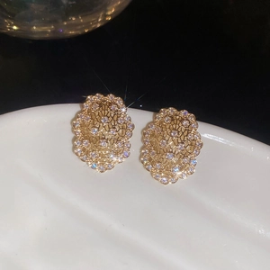 Vue détaillée de boucles d'oreilles ovales dorées avec zircons blancs sur un plateau