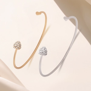 Detail of gold and silver open heart bracelets with pavé rhinestones on silk fabric