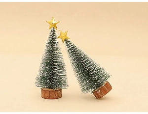 Detail of two miniature snow-flocked Christmas trees with gold stars on wood bases