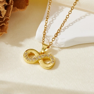 Gold infinity necklace with sparkling cubic zirconia on white stone and silk background