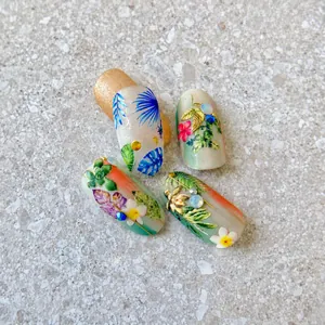 Vista macro detallada de pegatinas de uñas tropicales con hojas de palma y perlas 3D