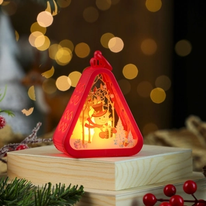 Detail of red Christmas lantern with snowman scene and warm LED light on wooden base