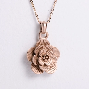 Macro shot of 3D rose gold flower pendant with layered petals and textured details