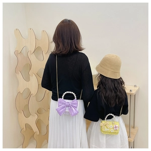 Detail of crossbody bags with pearl handles and bow decor for mothers and children
