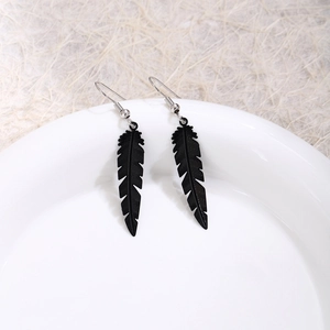 Detailed view of bohemian black feather hook earrings on a white ceramic plate