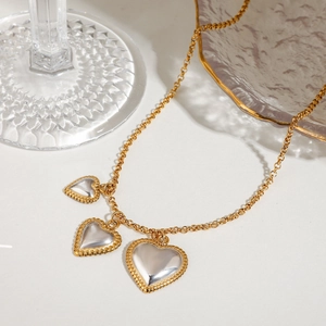 Two-tone stainless steel necklace featuring triple heart charms with gold beaded edges