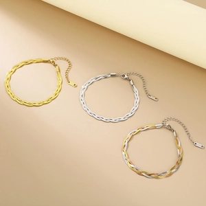 Dettaglio di bracciali a catena piatta intrecciata a tre fili in oro e argento acciaio