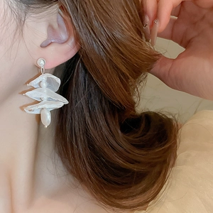 Detailed view of elegant white lace flower earrings with pearl on a female model