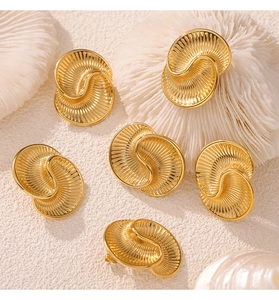 Detailed view of golden spiral textured teardrop earrings set with elegant wave patterns