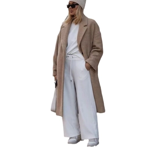 Vue complète d'une femme portant un long manteau en peluche avec bonnet et lunettes de soleil