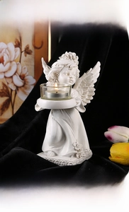 Detail of kneeling angel resin candle holder with intricate wing textures and floral base