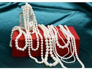 Detailed view of various baroque pearl necklaces on elegant dark green silk background