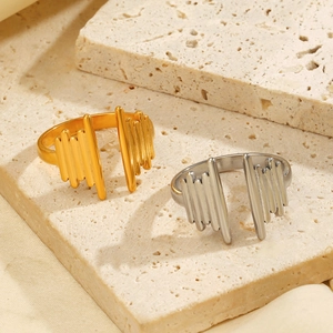 Minimalist wave-shaped 18K gold and silver open rings displayed on a stone pedestal